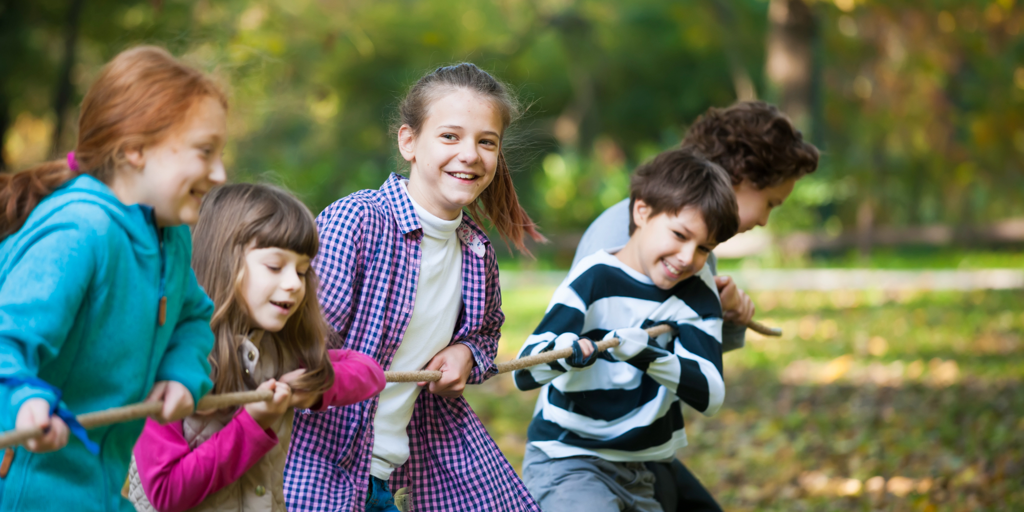 Enkele kinderen trekken vol overgave aan een touw in het park. Enkele kinderen trekken vol overgave aan een touw in het park.